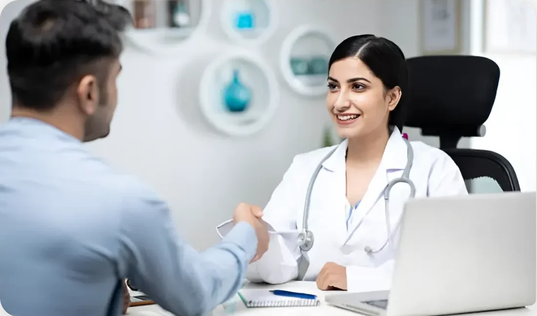 Smiling female doctor shaking hands with a patient in her office, symbolizing trust and positive doctor-patient relationship.