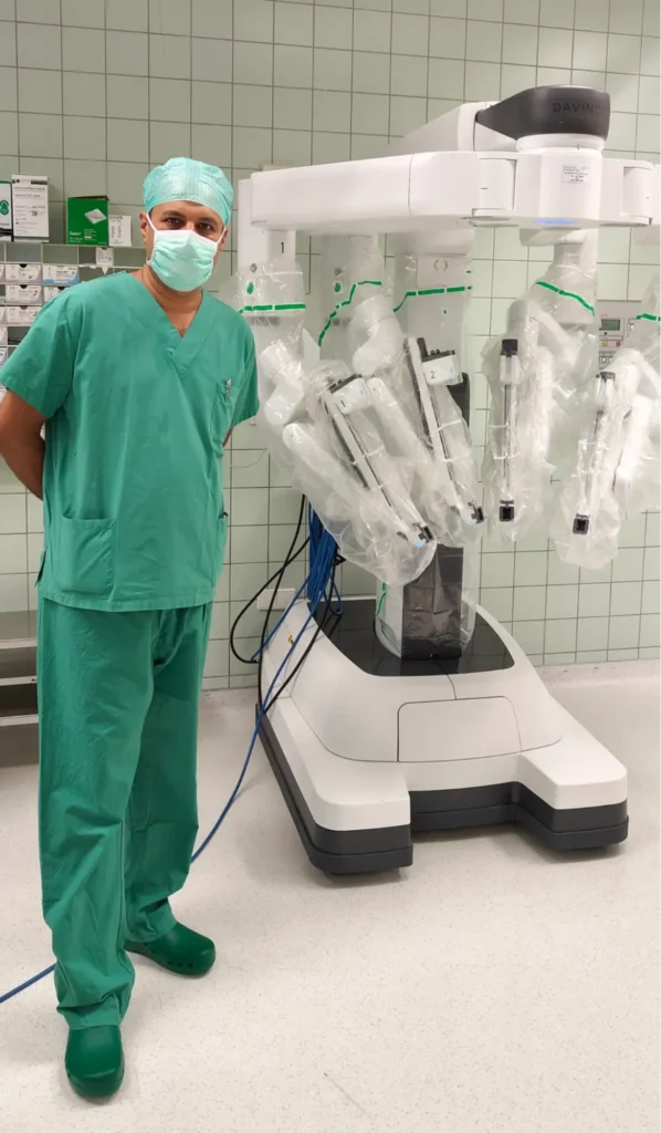 Surgeon in green scrubs standing next to Da Vinci robotic surgery system