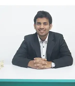 Dr. Pharande seated at a white desk in a formal black suit smiling confidently