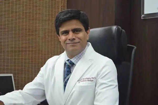 male surgeon in white coat sitting at clinic desk portrait