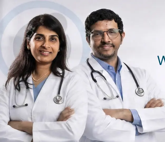 Dr Geetha Iyer and Dr Bhaskar Srinivasan posing together in white coats with stethoscopes