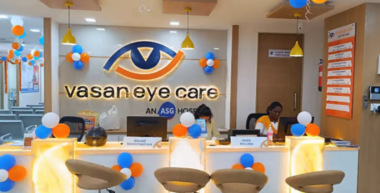 Vasan Eye Care hospital reception area with registration desks, staff, patient seating, and eye care branding