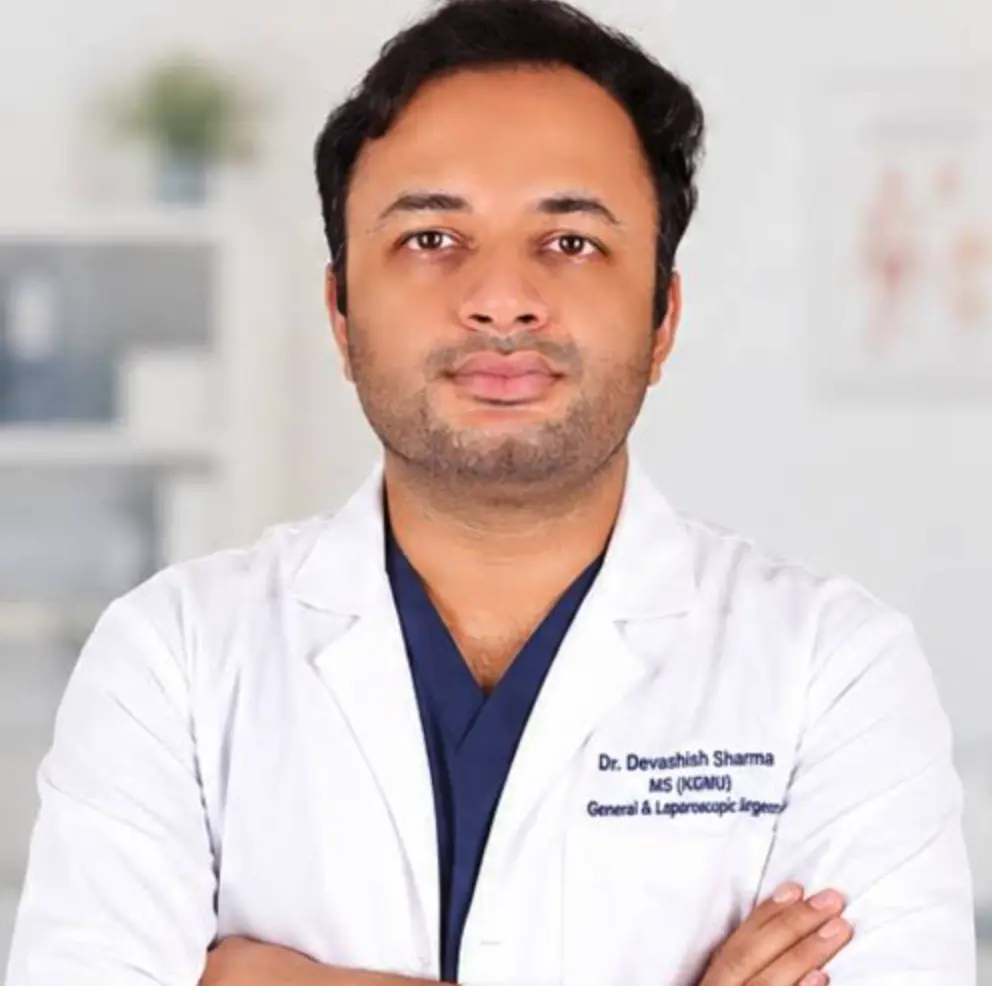 Dr. Devashish Sharma, general and laparoscopic surgeon, in a white coat over navy scrubs