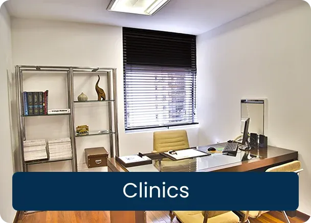 Clinics: an empty consulting room with a wooden desk, two chairs, shelves and a window with blinds